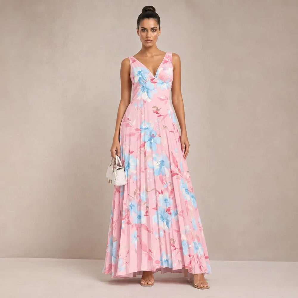 Woman in pink pleated floral maxi dress standing in contrapposto pose