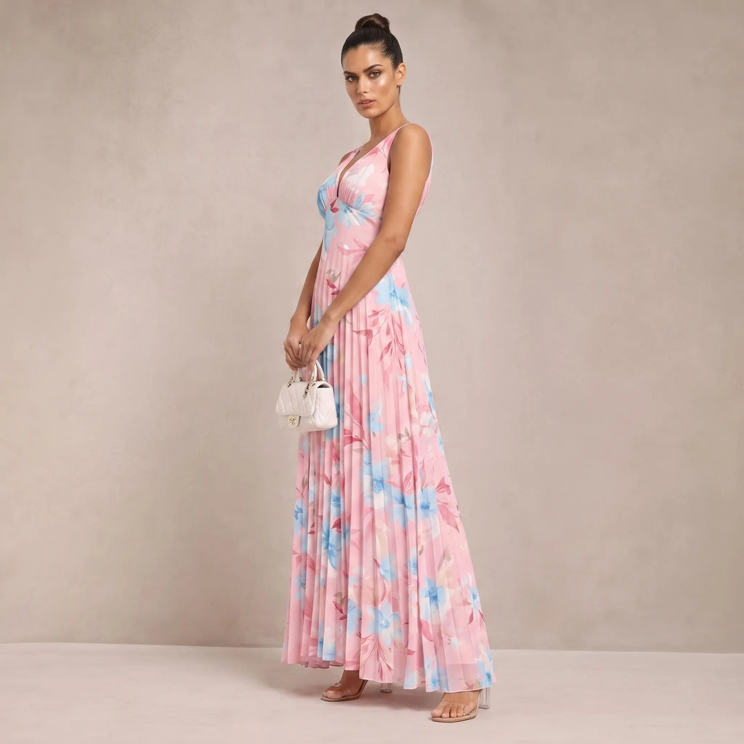 Woman in pink pleated floral maxi dress shown from a three-quarter angle