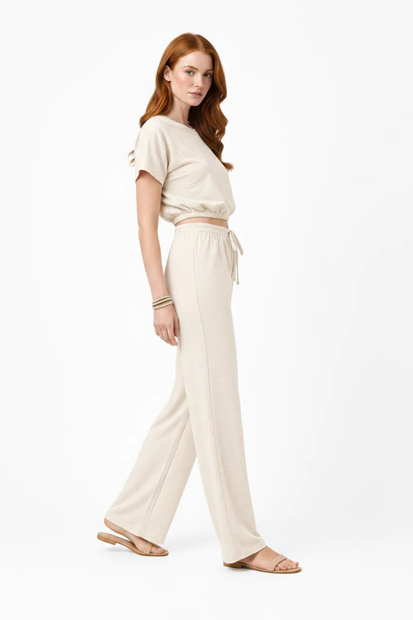 Beige crop top and wide-leg trouser co-ord set on model in three-quarter turn