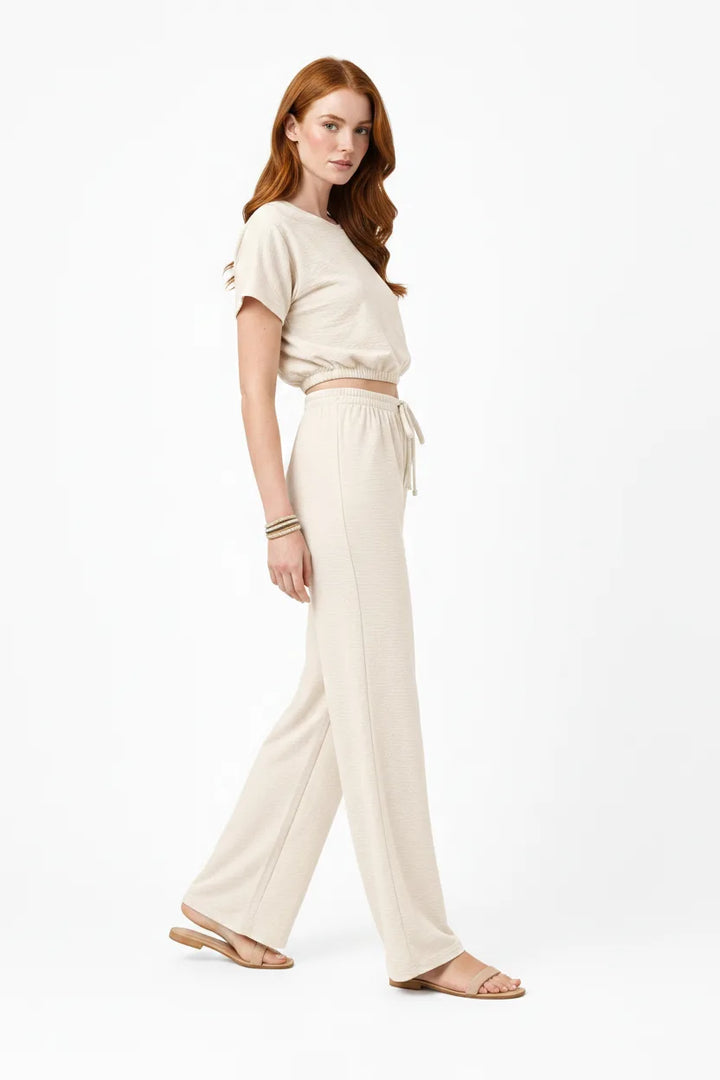 Beige crop top and wide-leg trouser co-ord set on model in three-quarter turn