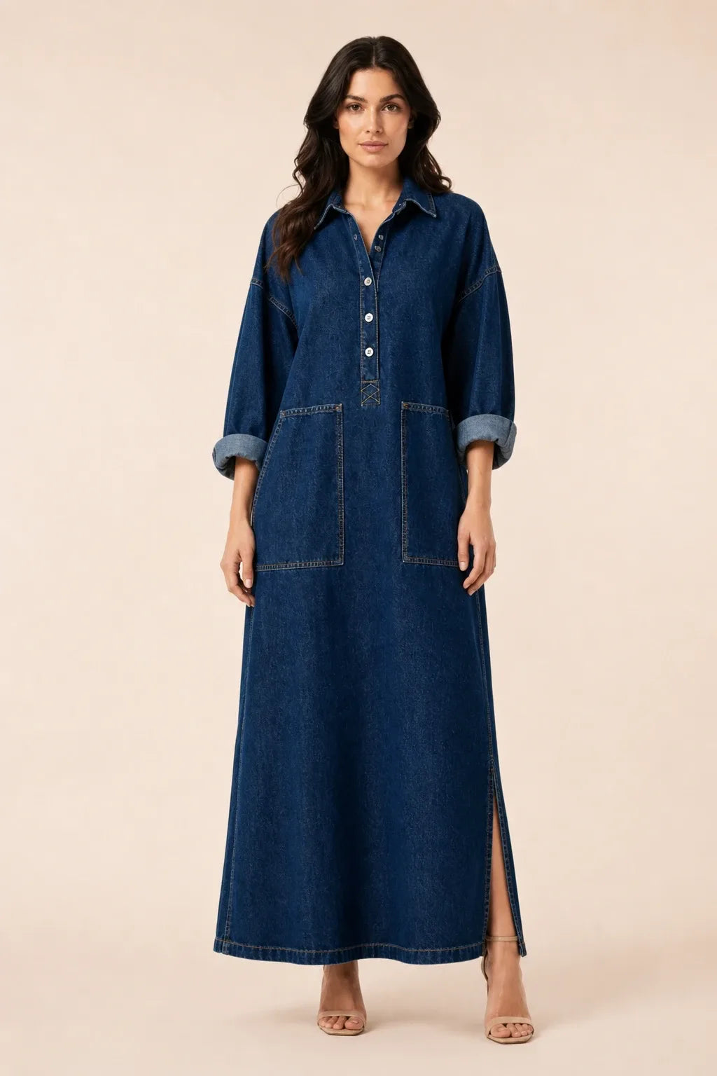 Blue denim maxi dress on model in contrapposto stance, button-front closure and relaxed silhouette