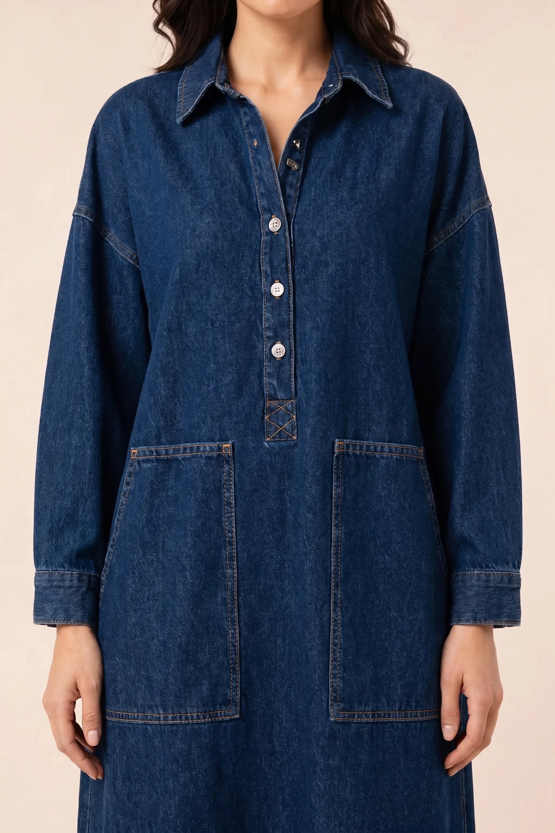 Close-up detail of blue denim maxi dress fabric, stitching, and button placket