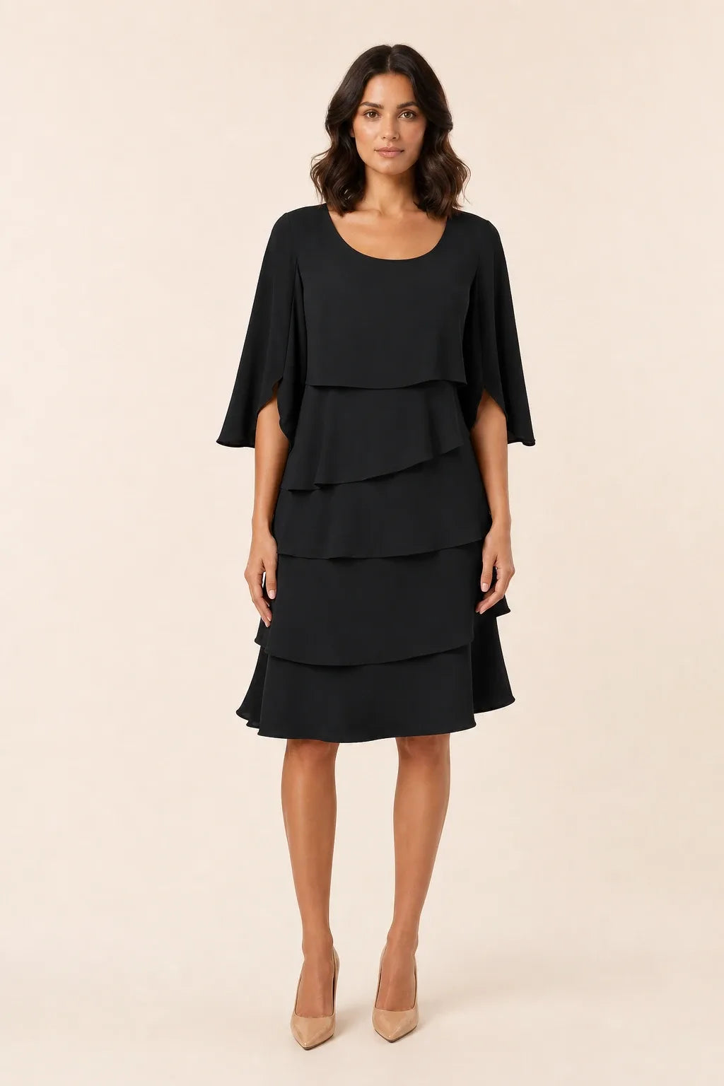 Black tiered cape dress with flowing layers on a model in a contrapposto stance