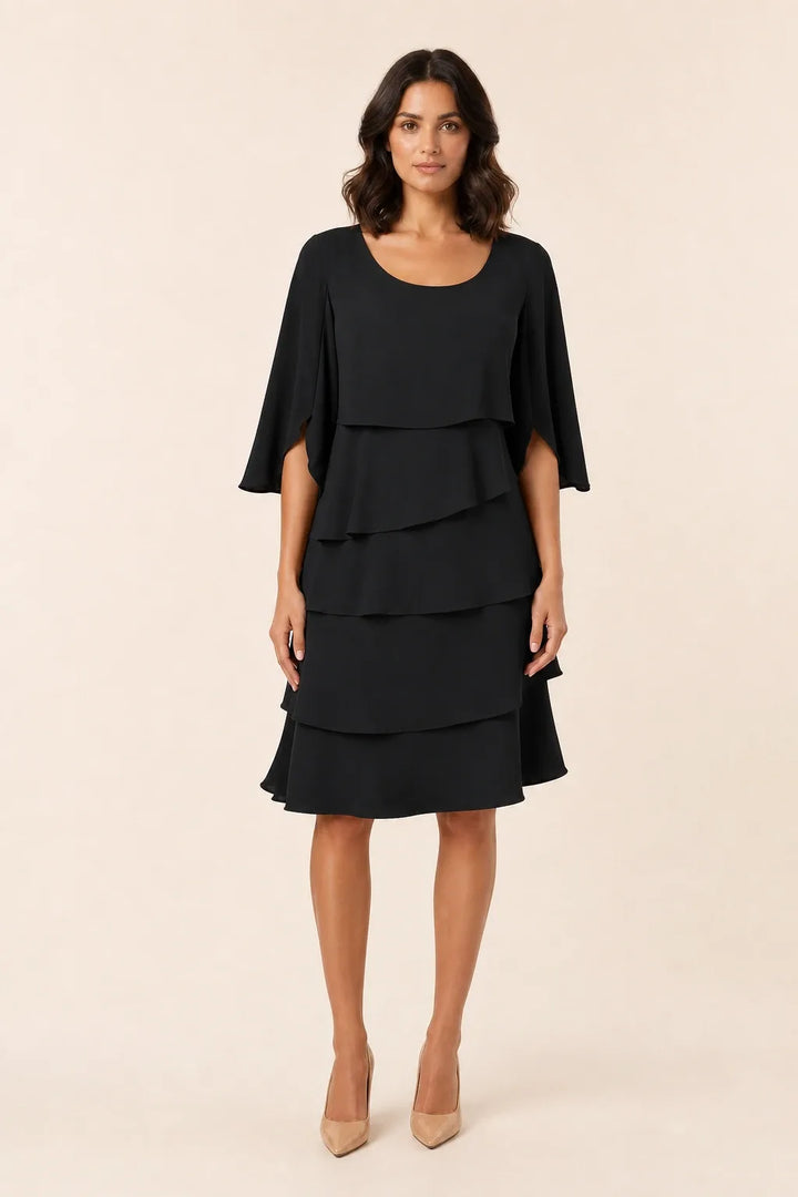 Black tiered cape dress with flowing layers on a model in a contrapposto stance