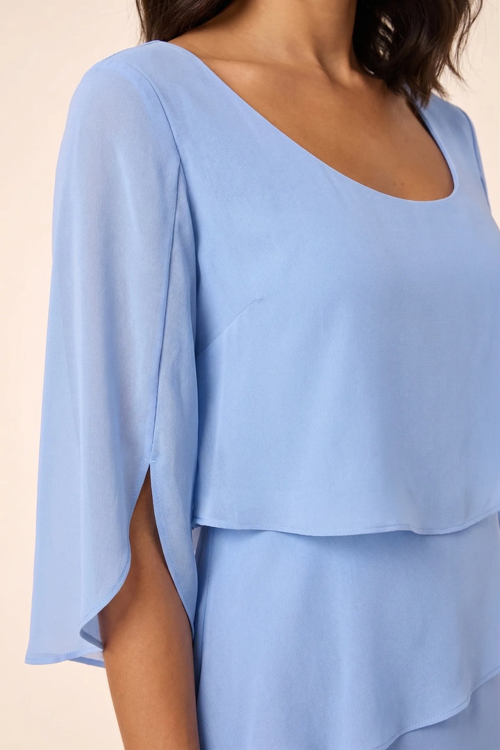 Close-up detail of blue tiered cape dress showing layered fabric texture