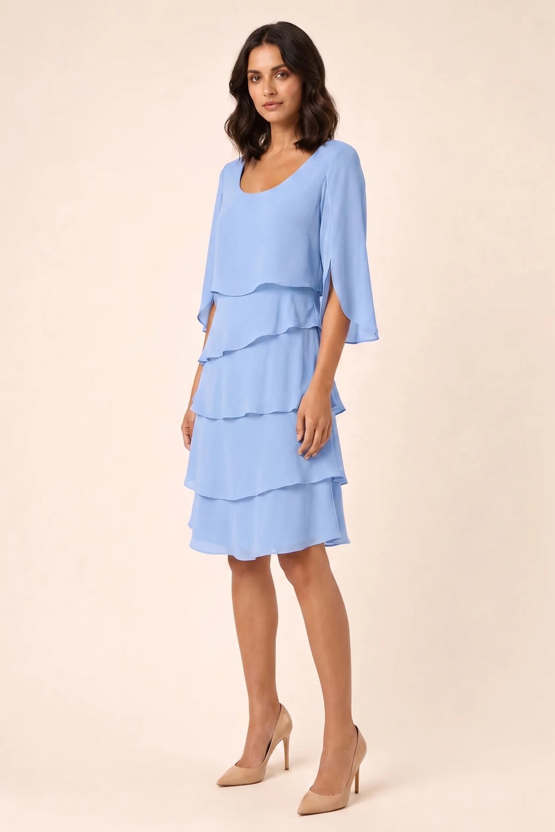 Blue tiered cape dress with flowing layers on a model in a three-quarter turn