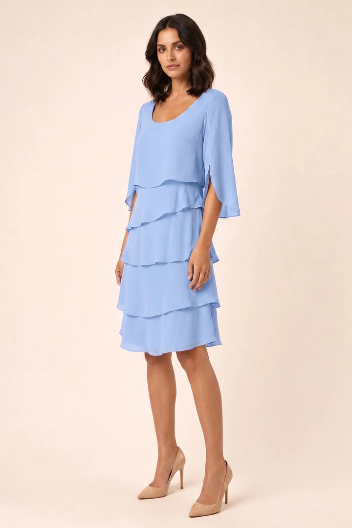 Blue tiered cape dress with flowing layers on a model in a three-quarter turn