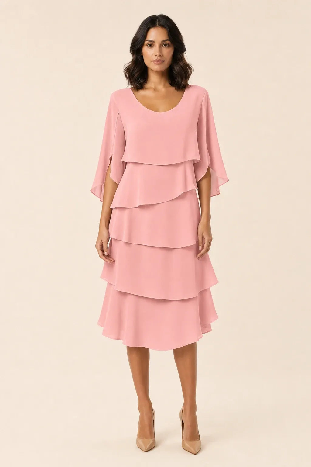 Pink tiered cape dress with flowing layers on a model in a contrapposto stance