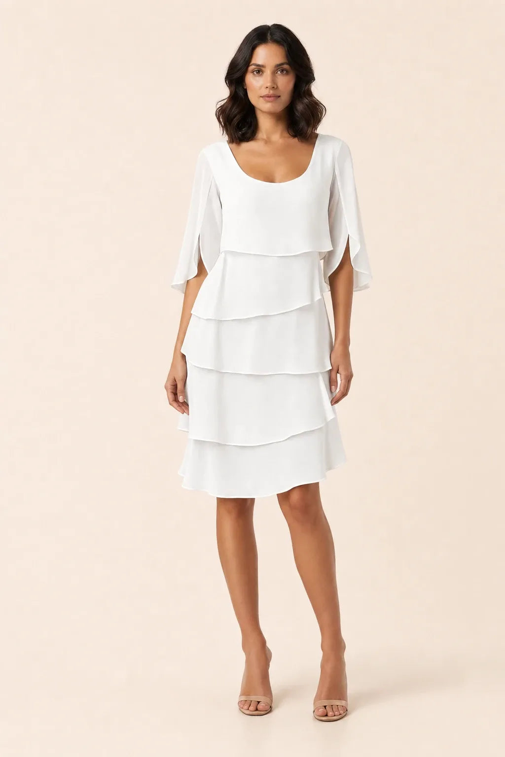 White tiered cape dress with flowing layers on a model in a contrapposto stance