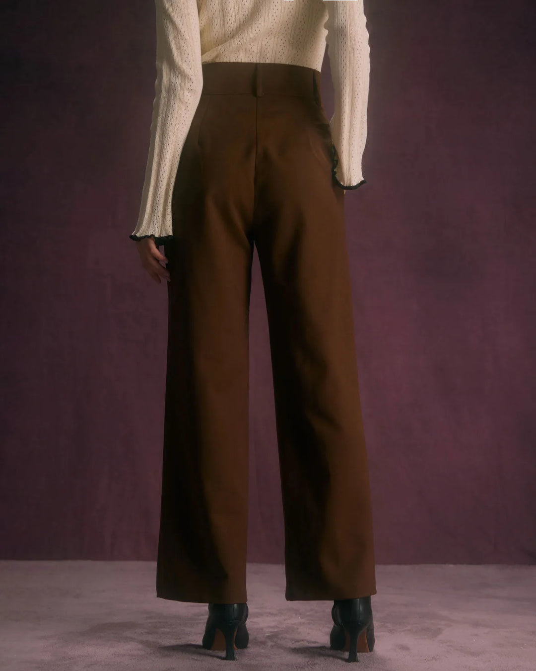 Side view of model in wide-leg coffee brown trousers highlighting the fluid leg opening and rise