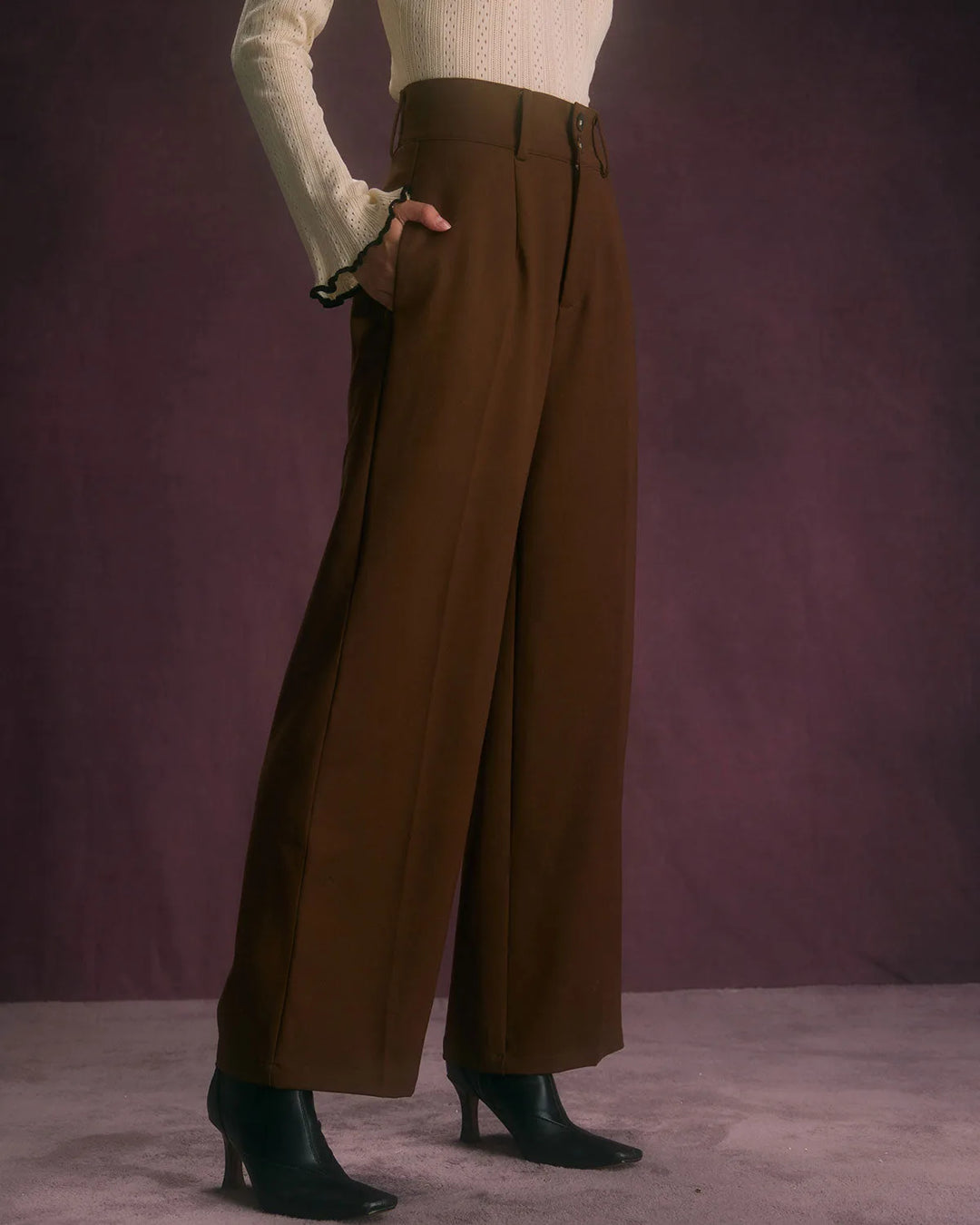 Model at a three-quarter angle in wide-leg coffee brown trousers showing drape and silhouette