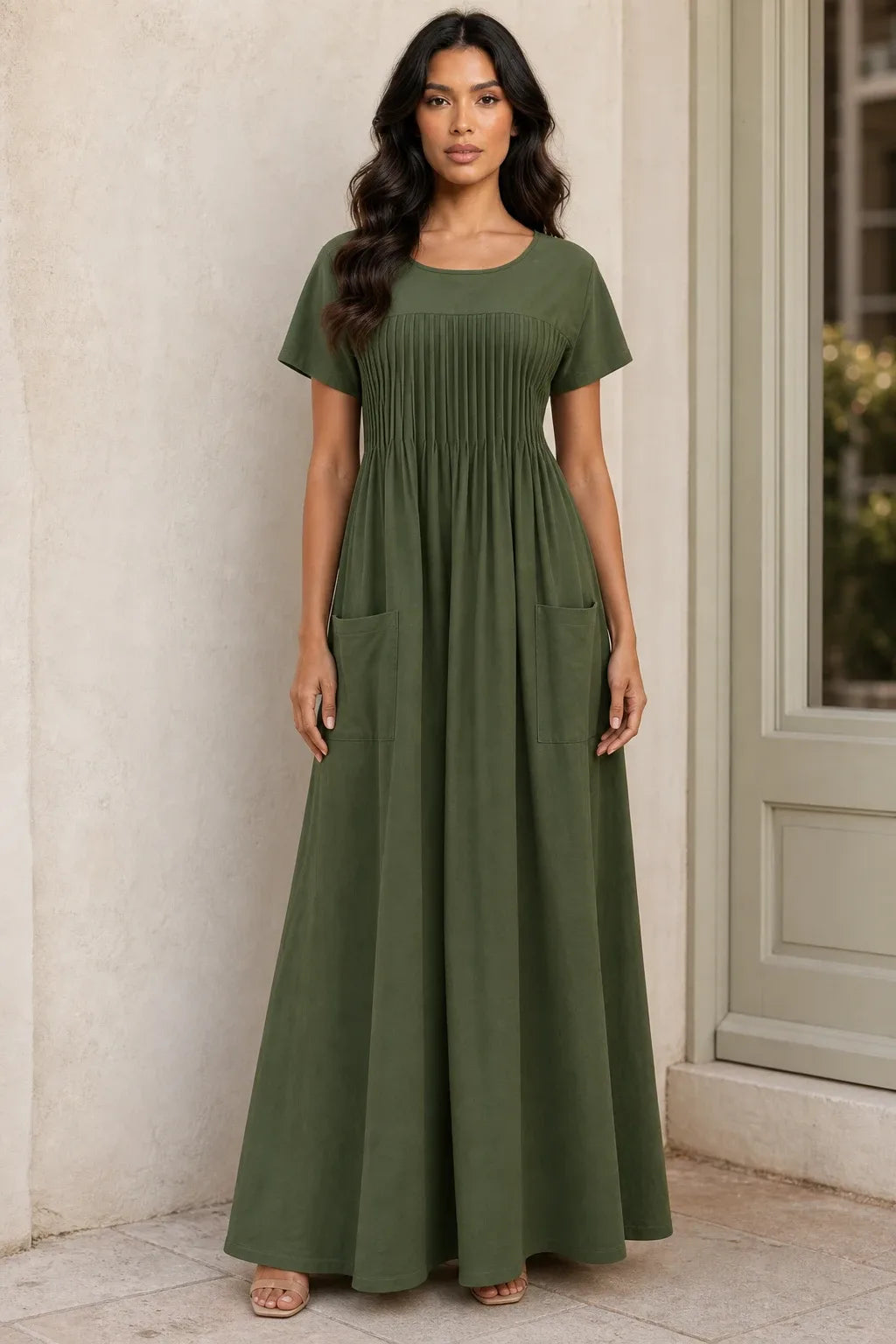 Green pintuck midi dress on model in contrapposto stance, fitted bodice with vertical pleat detailing