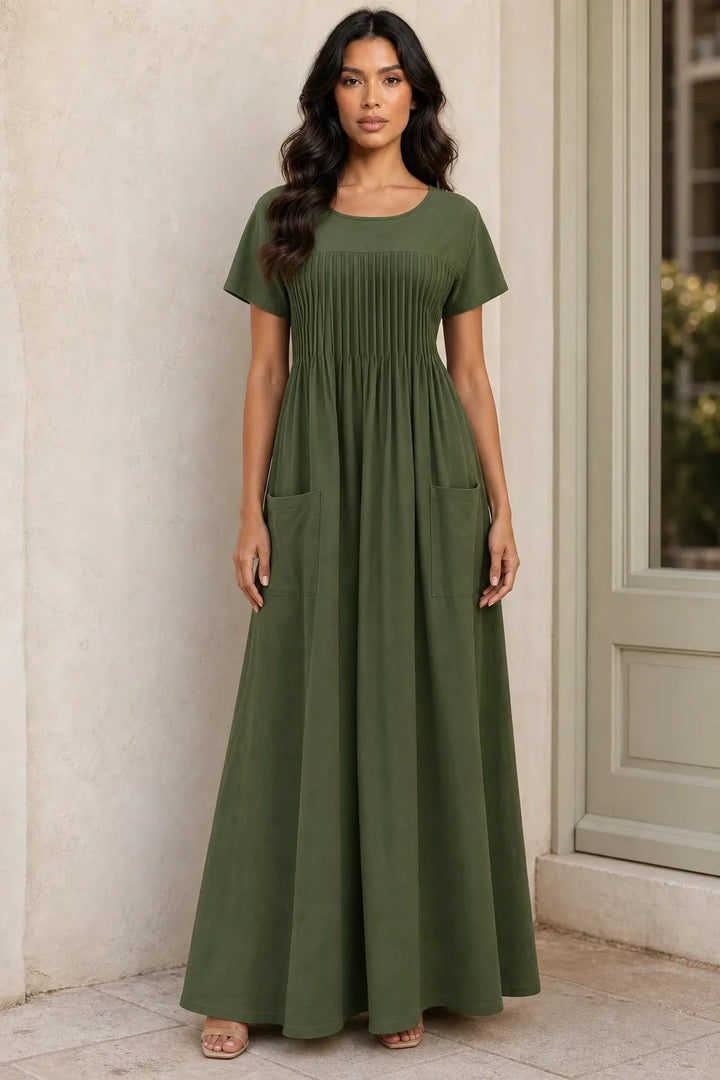 Green pintuck midi dress on model in contrapposto stance, fitted bodice with vertical pleat detailing