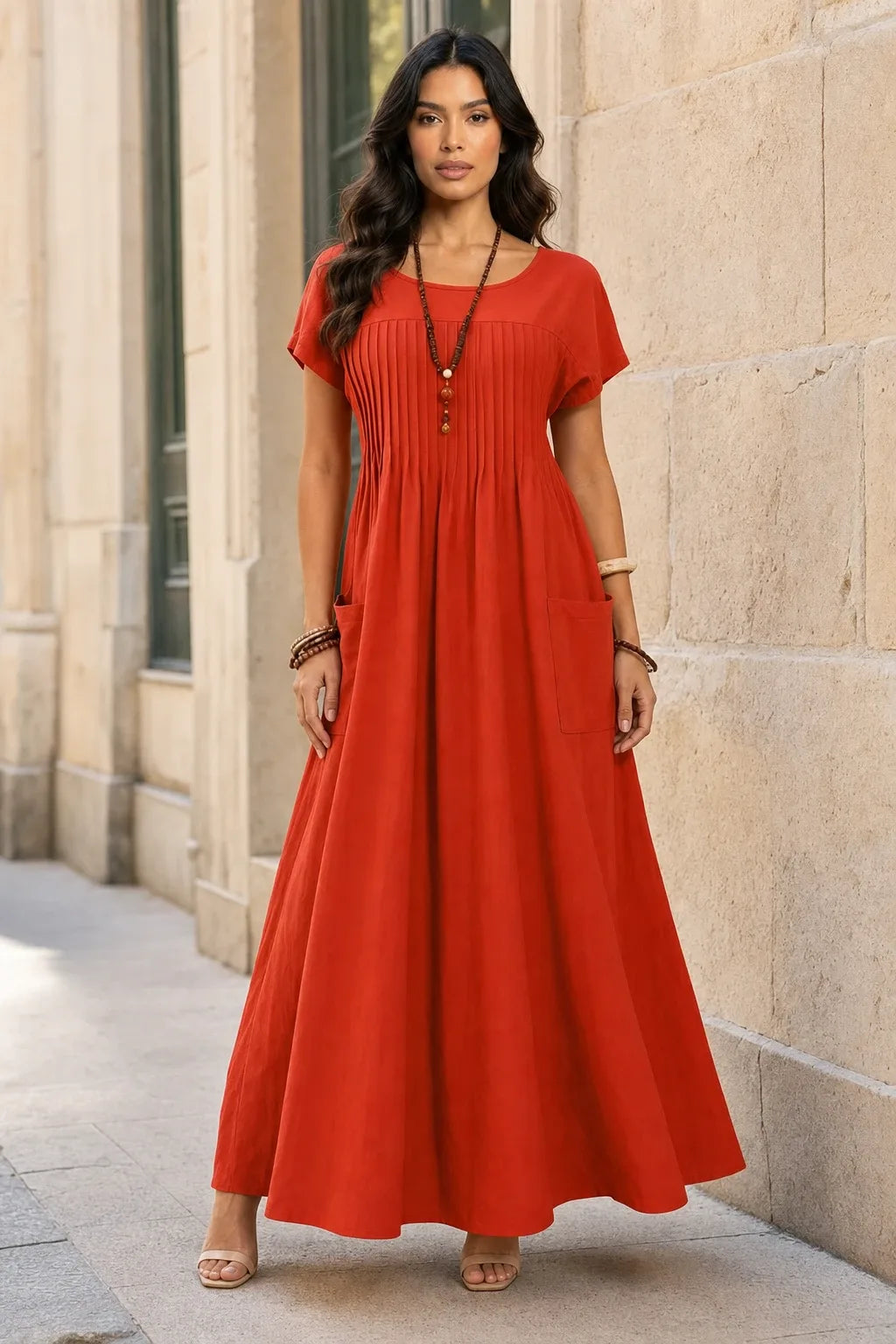 Orange pintuck midi dress on model in contrapposto stance, fitted bodice with vertical pleat detailing