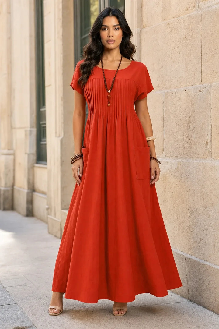 Orange pintuck midi dress on model in contrapposto stance, fitted bodice with vertical pleat detailing