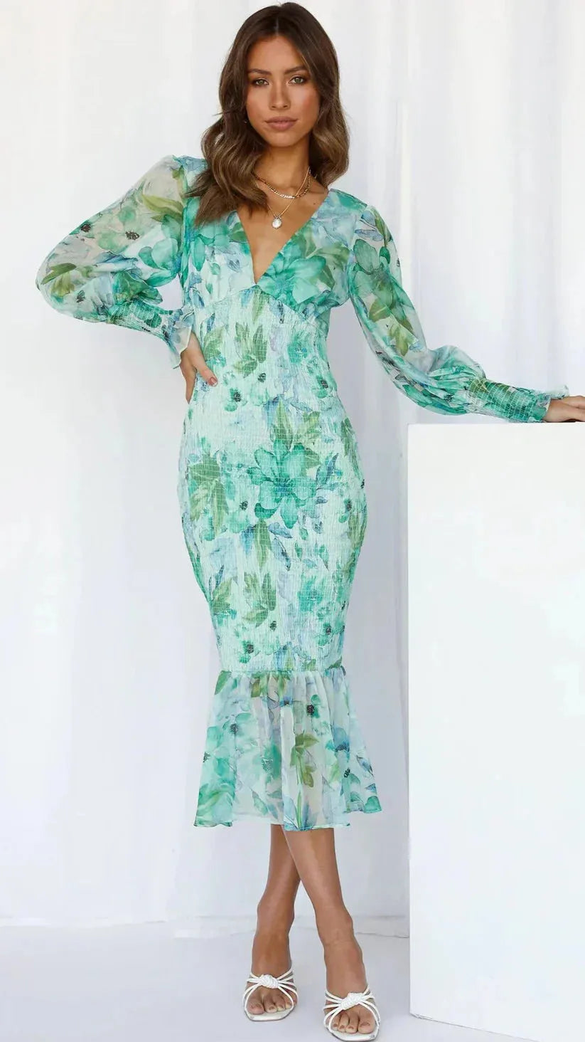 Woman wearing a green floral mermaid midi dress with fitted bodice and flared hem