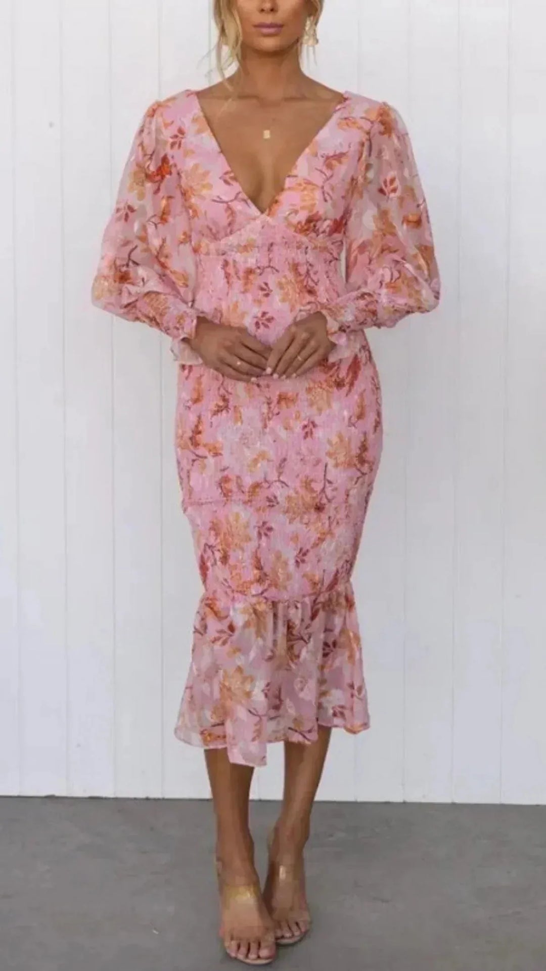 Woman facing forward in a pink floral mermaid midi dress with fitted bodice and flared hem