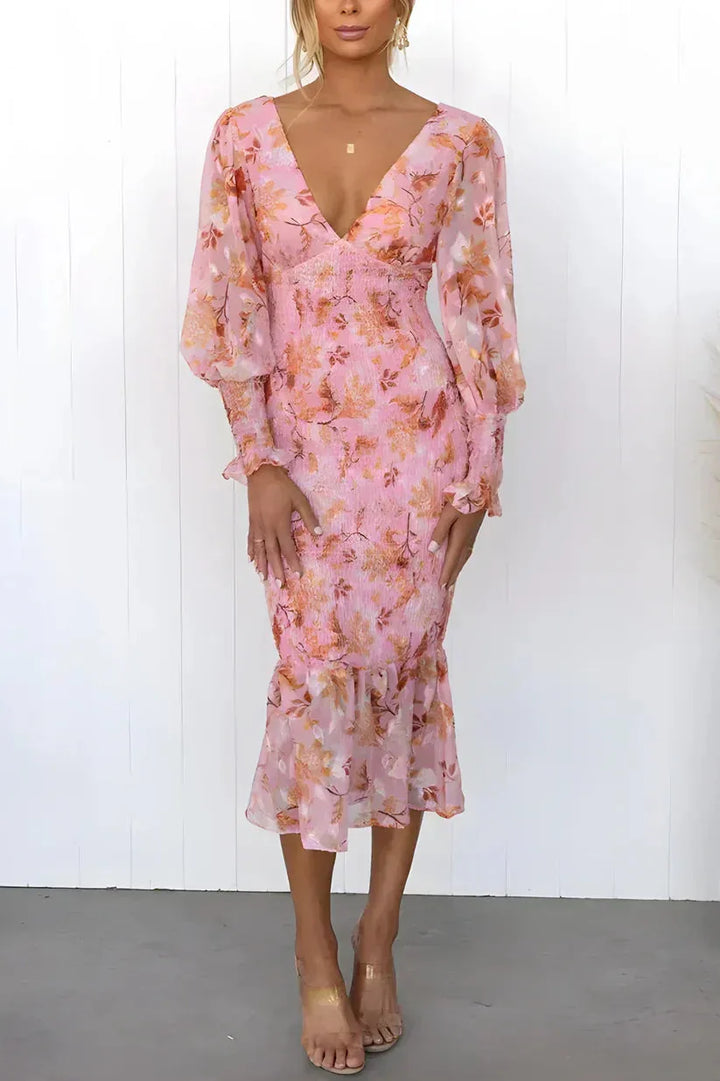 Woman in a three-quarter turn wearing a pink floral mermaid midi dress with ruched detailing