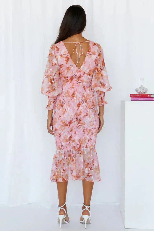 Woman posing in a pink floral mermaid midi dress with form-fitting silhouette