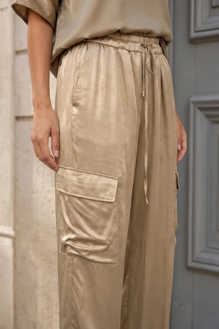 Close-up detail of gold satin cargo co-ord fabric and hardware