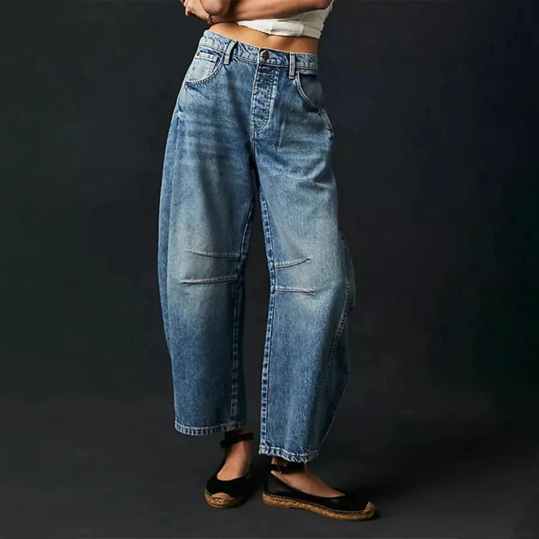 Dark blue barrel leg jeans on model, three-quarter turn highlighting curved leg shape