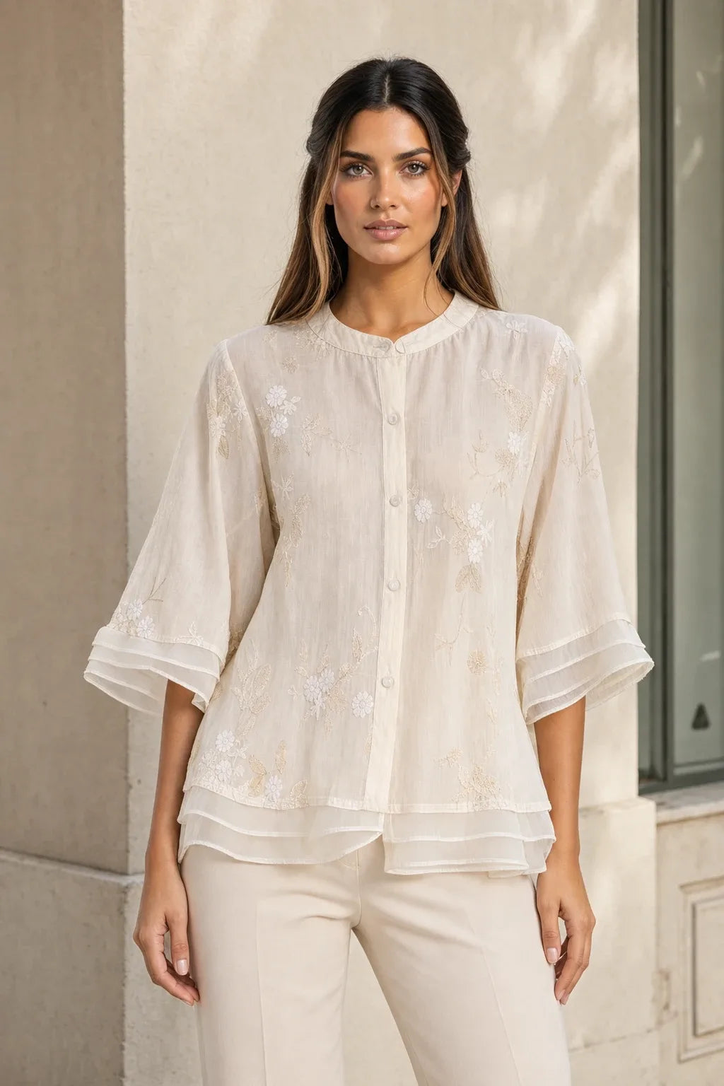 Beige embroidered mesh overlay blouse on model in contrapposto stance