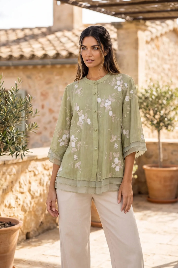 Model wearing green embroidered mesh overlay blouse in lifestyle setting
