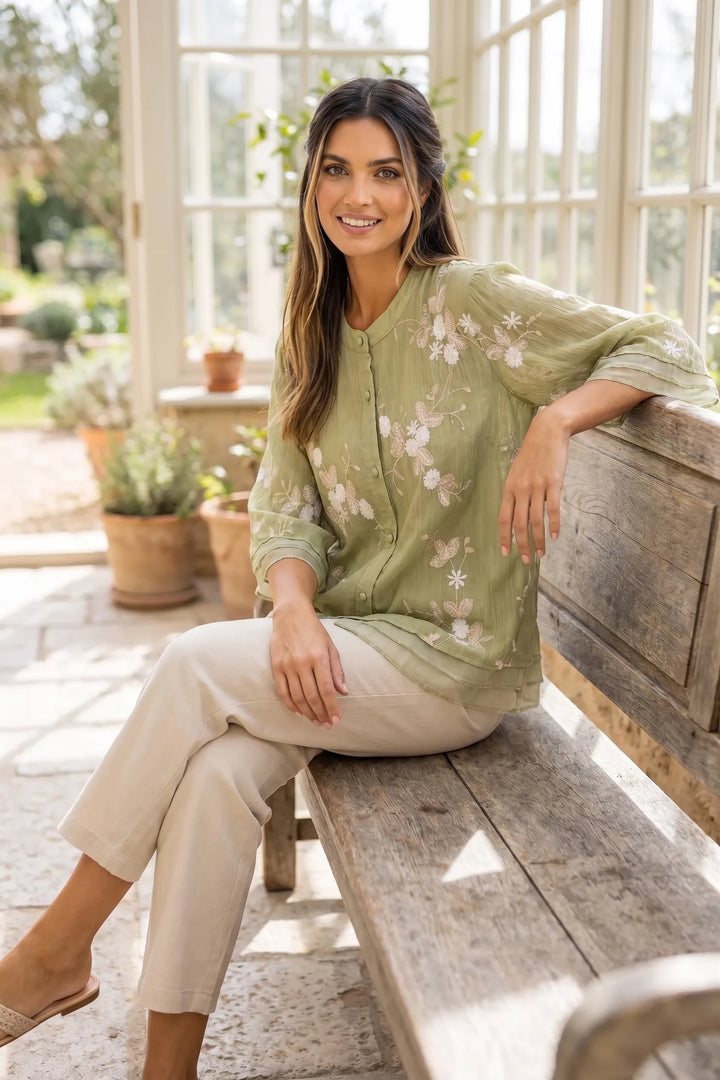 Model wearing green embroidered mesh overlay blouse in outdoor lifestyle setting