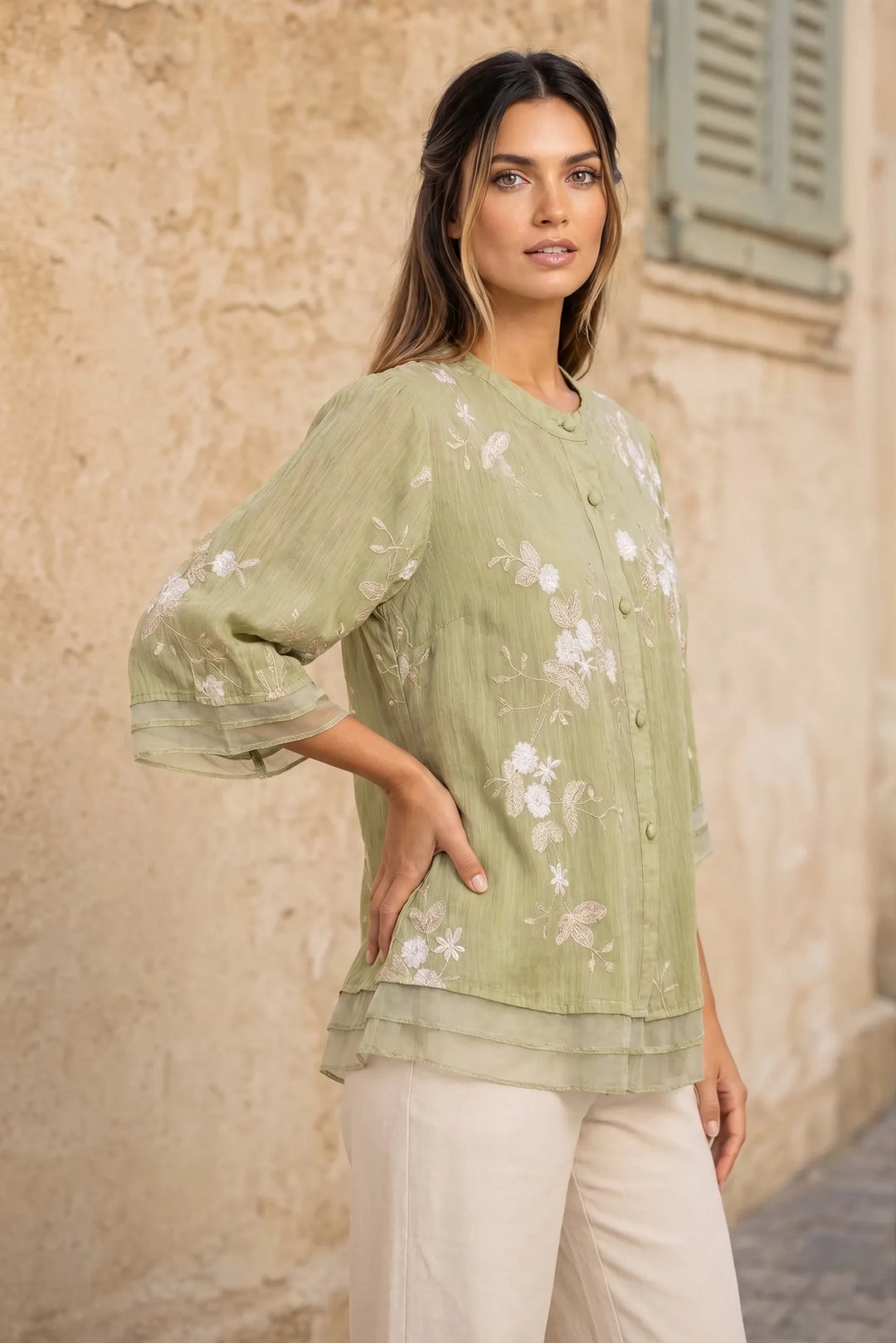 Green embroidered mesh overlay blouse on model in three-quarter turn