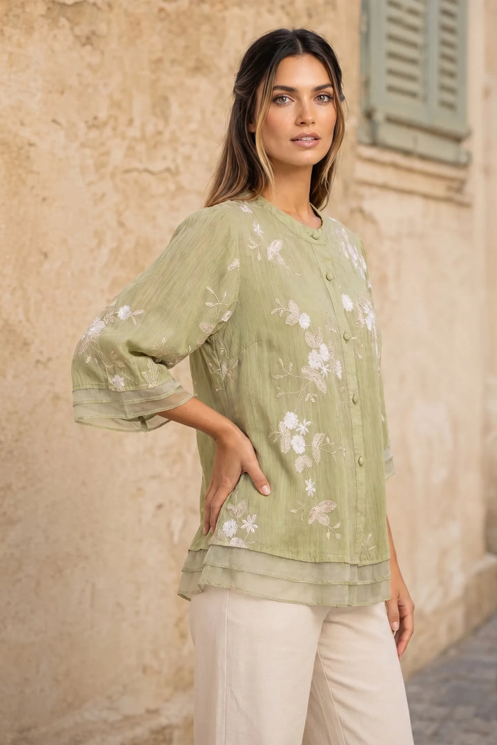 Green embroidered mesh overlay blouse on model in three-quarter turn