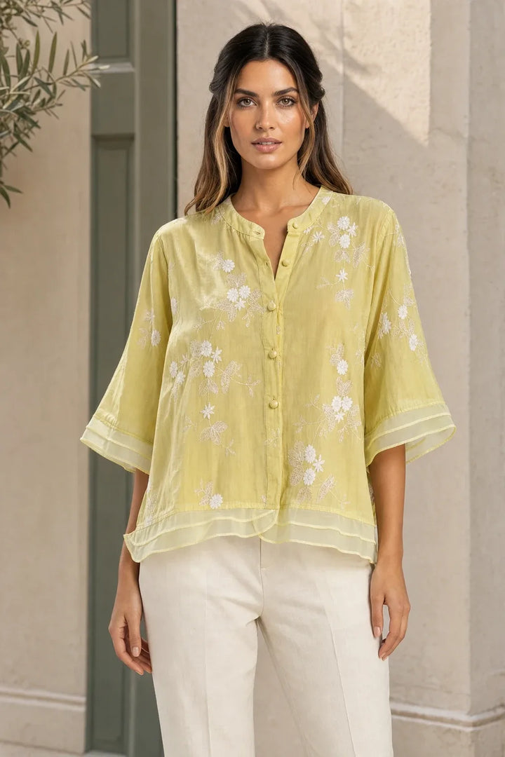 Yellow embroidered mesh overlay blouse on model in contrapposto stance