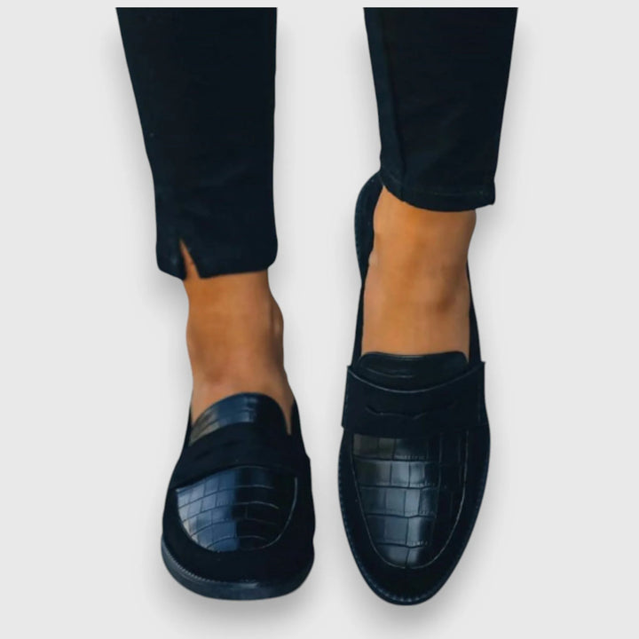 Heel view of a croc panel penny loafer showing back construction and sole