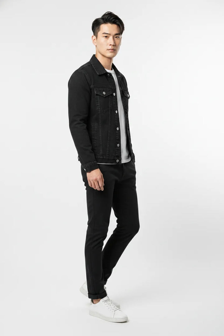 Black denim trucker jacket on model at three-quarter turn