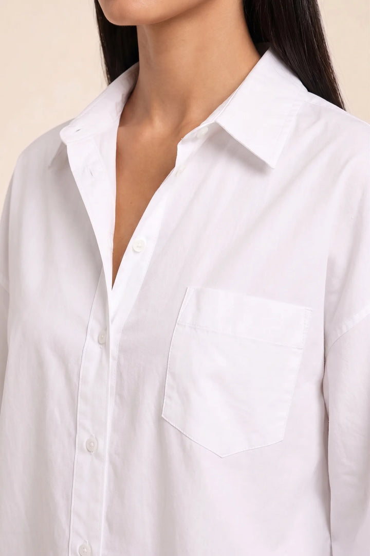 Close-up detail of white oversized button-down shirt fabric and buttons