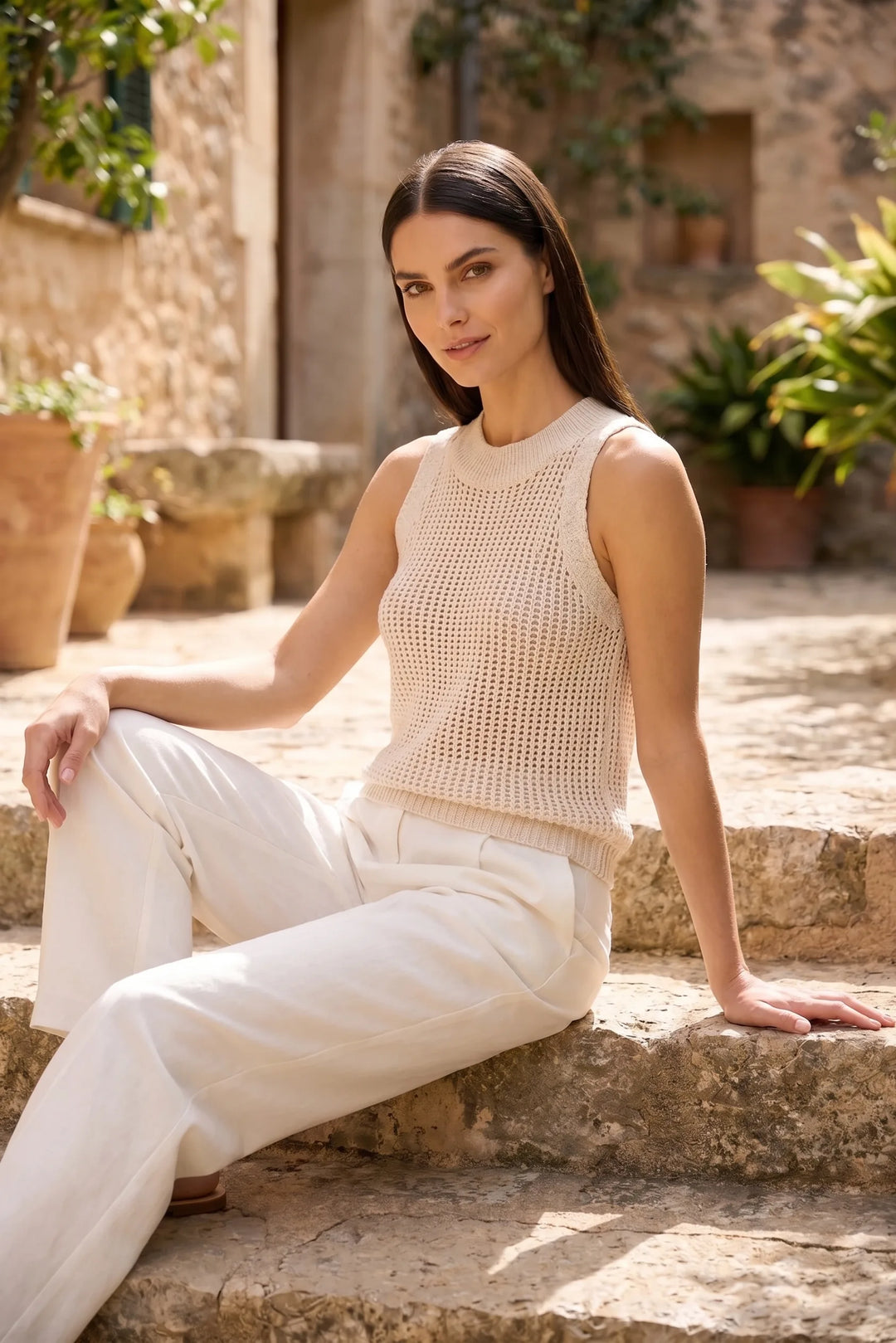 Model wearing apricot open knit tank top in an outdoor lifestyle setting