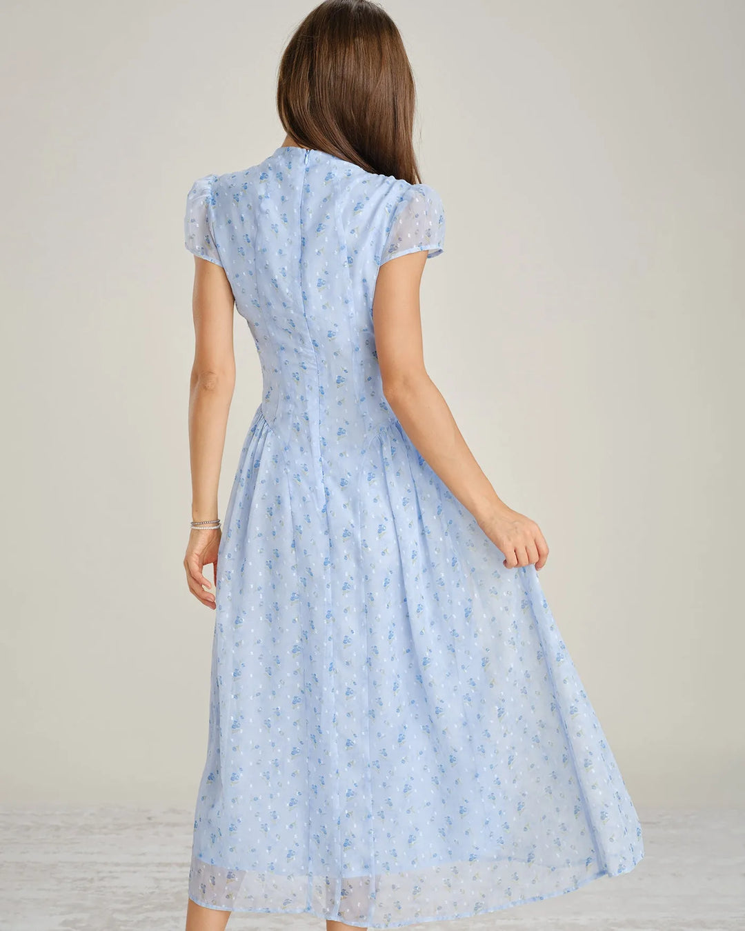 Model wearing a blue chiffon drop waist midi dress in an alternate pose