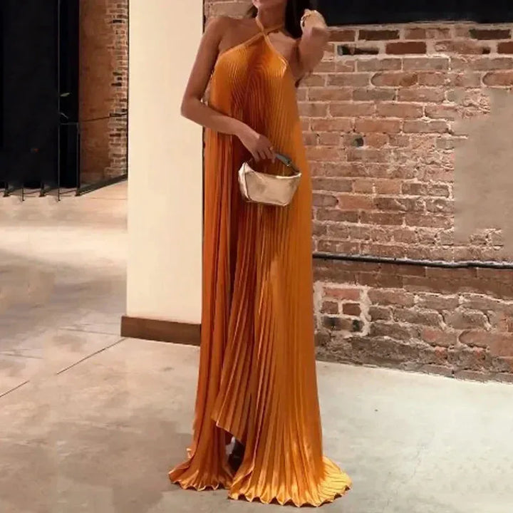 Orange pleated halter maxi dress on model from the side, showing silhouette