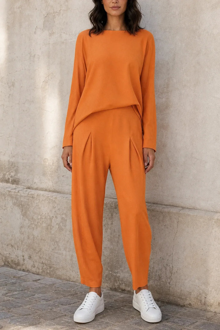 Orange bateau neck knit trouser set on model in contrapposto stance