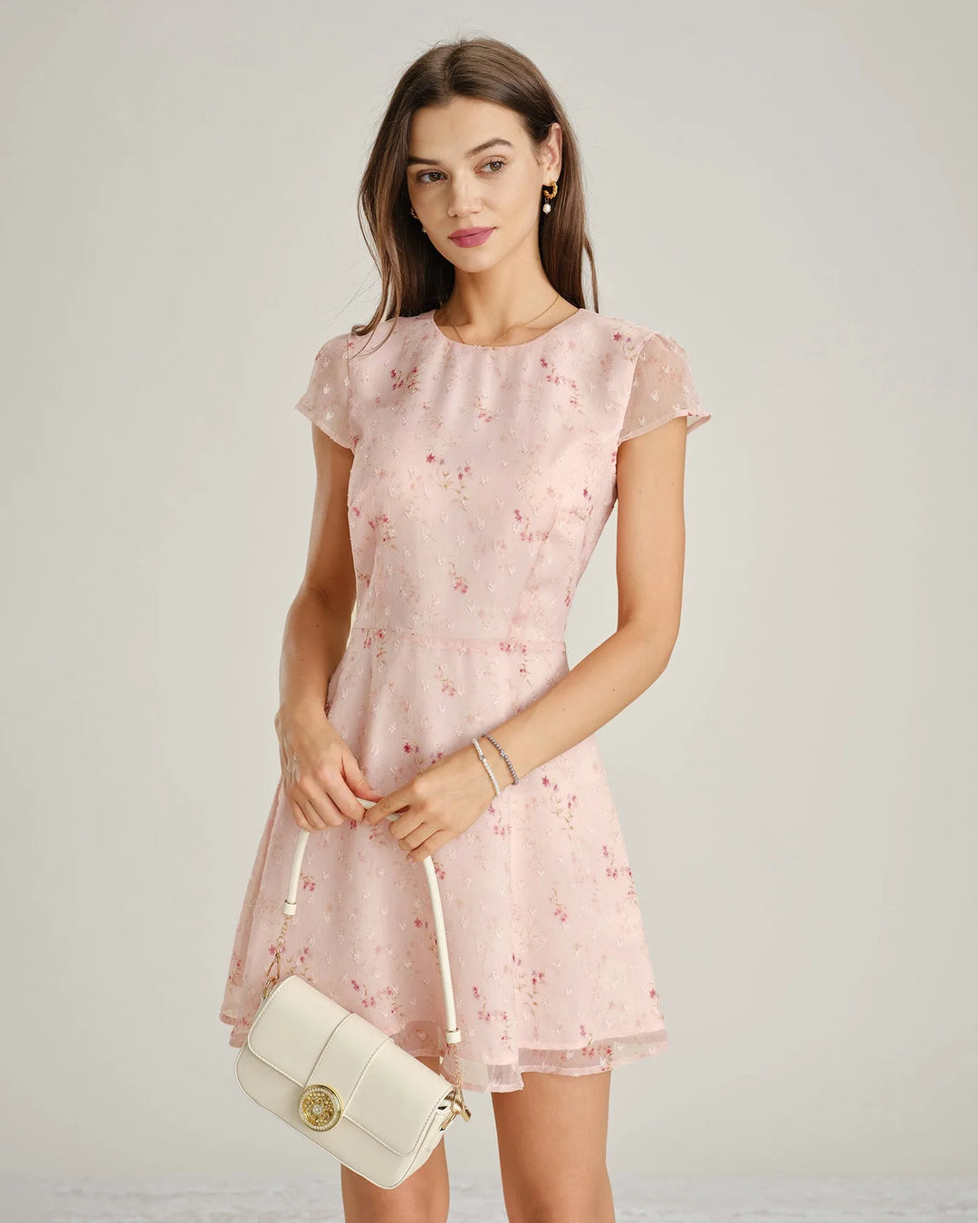 Woman facing forward in a pink floral embroidered mini dress