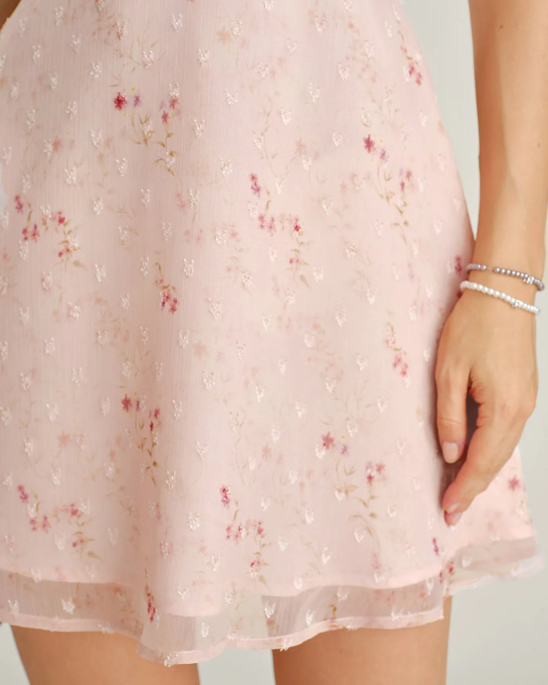 Woman in a pink floral embroidered mini dress at a three-quarter turn