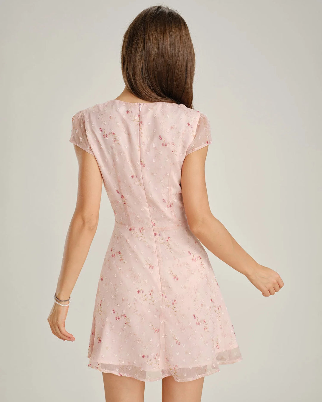 Woman posing in a pink floral embroidered mini dress