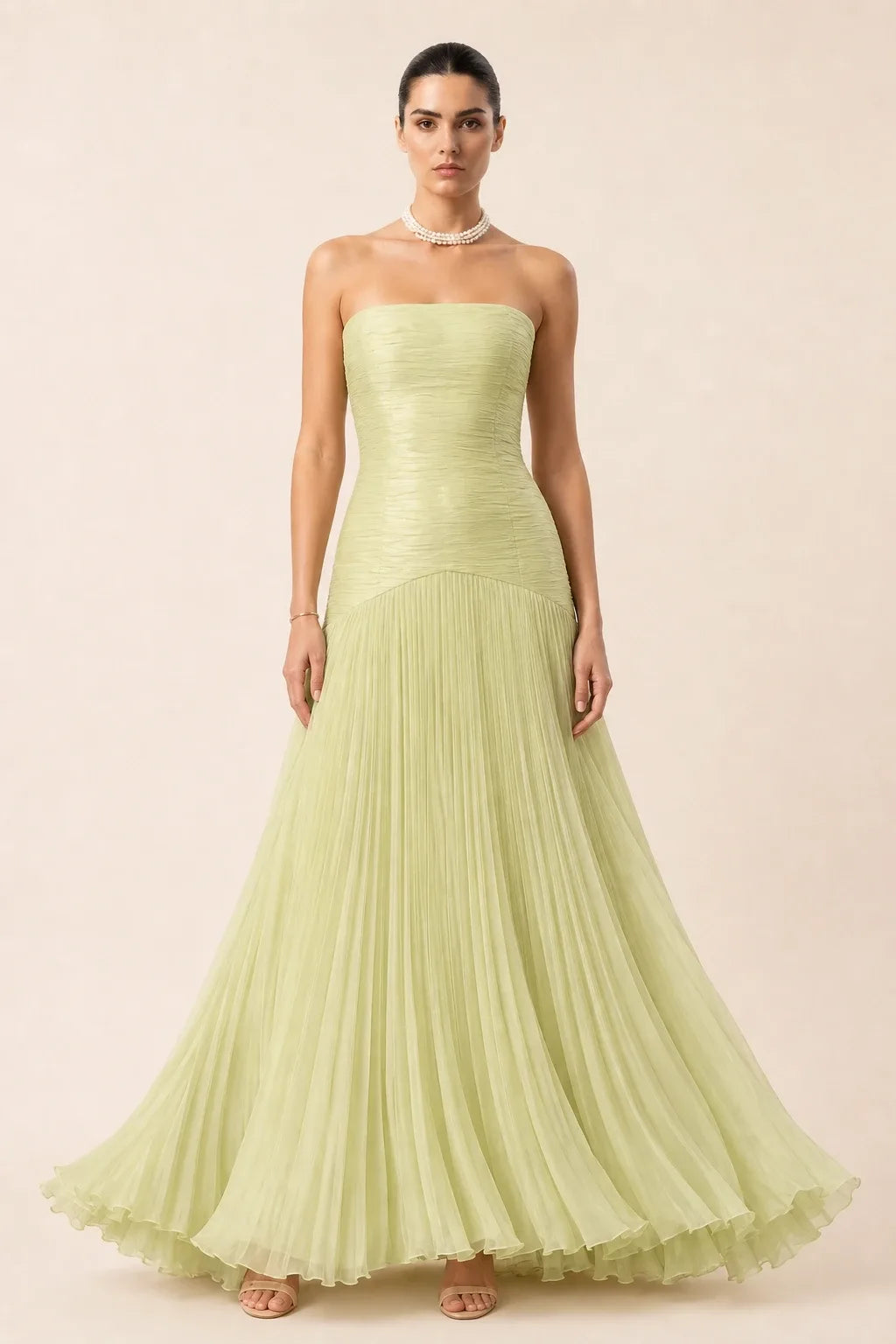 Emerald green pleated drop waist gown on a model in a contrapposto stance