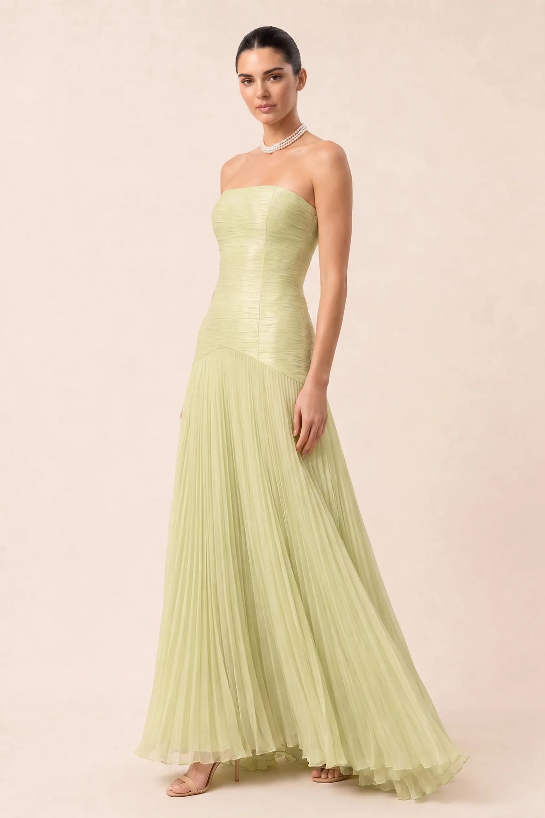 Emerald green pleated drop waist gown on a model in a three-quarter turn