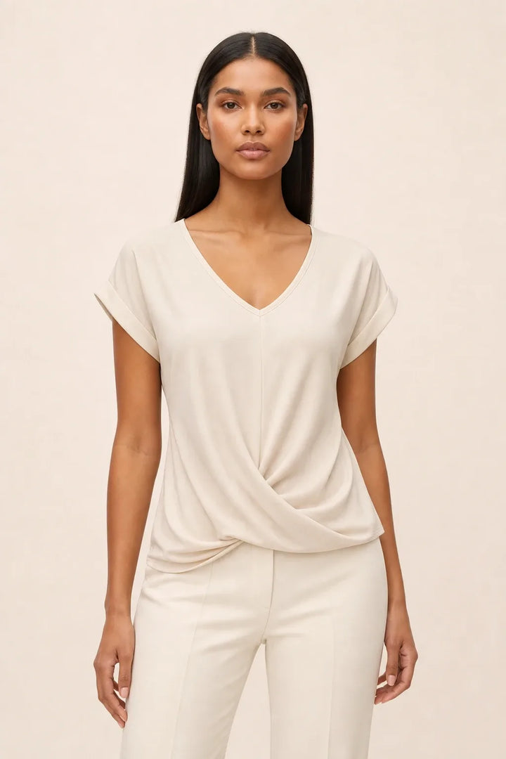 Apricot twist-front cap sleeve top on a model in a contrapposto stance
