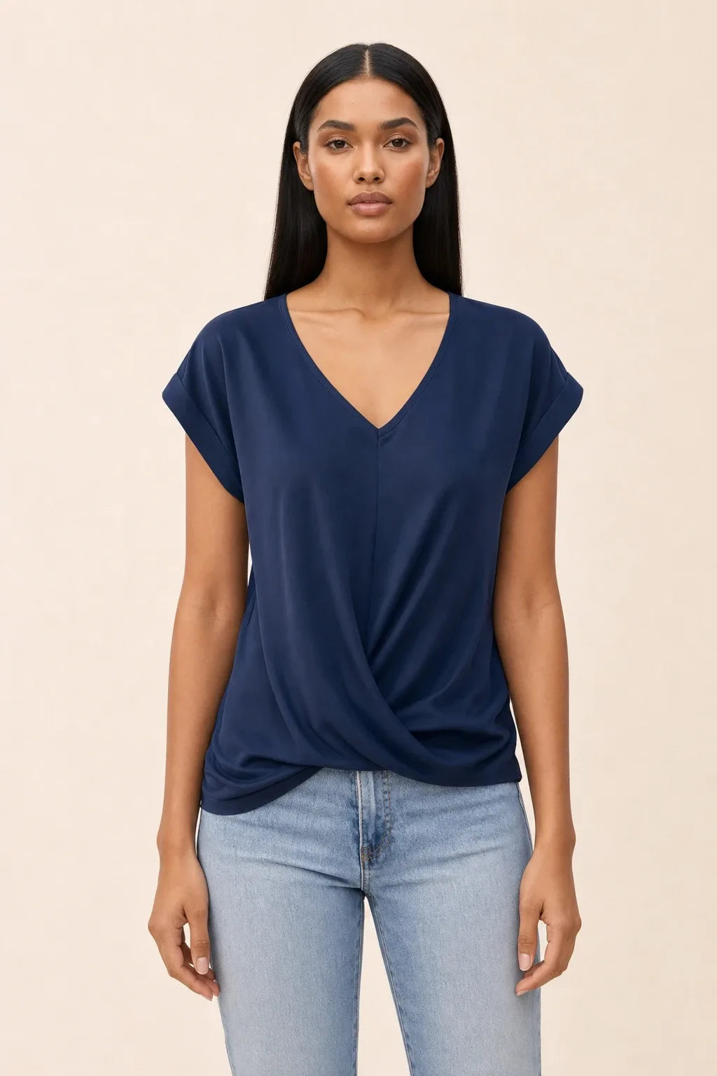 Blue twist-front cap sleeve top on a model in a contrapposto stance