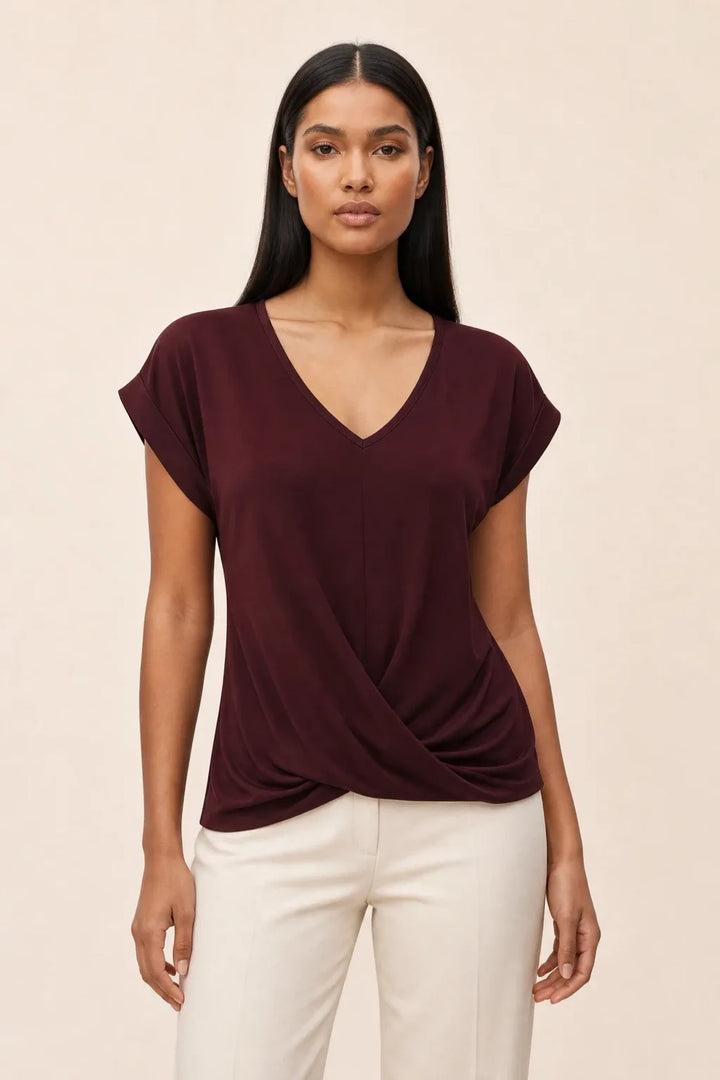 Burgundy twist-front cap sleeve top on a model in a contrapposto stance