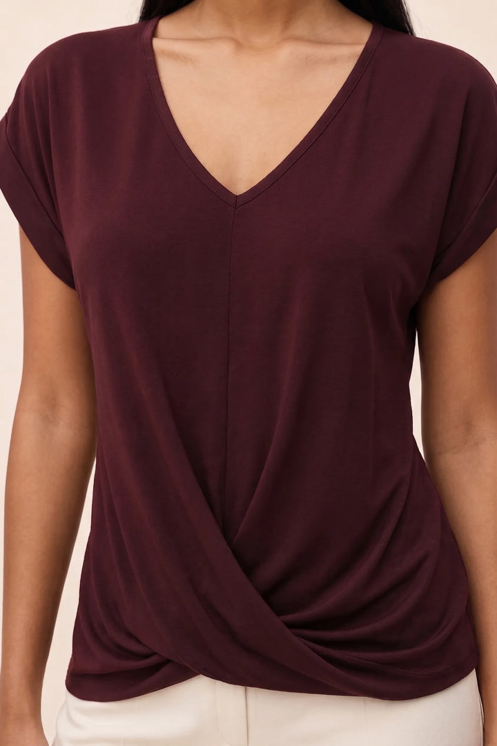 Close-up detail of the twisted front neckline on a burgundy cap sleeve top