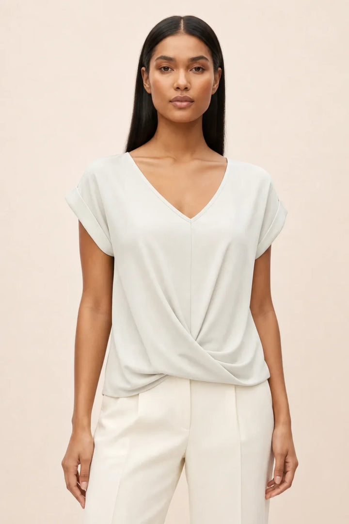 White twist-front cap sleeve top on a model in a contrapposto stance