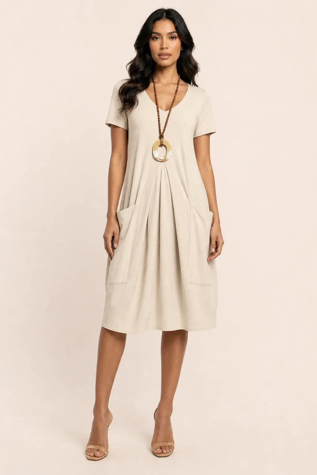 Beige flowy midi dress with pockets on model in contrapposto stance