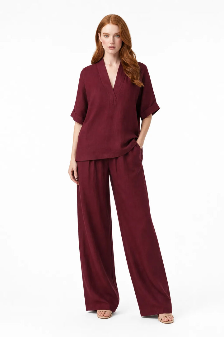 Burgundy linen kimono jacket and wide-leg trousers on a model in a contrapposto stance